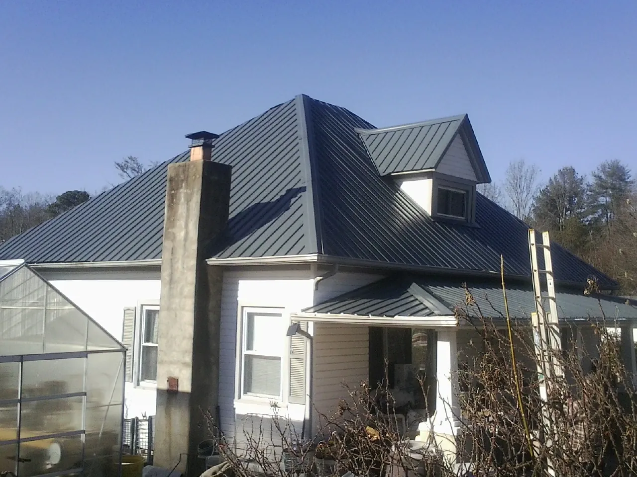 Dark blue standing seam metal roof on a white farmhouse with dormer — Slate & Tile Roof Repair by Roofing Brothers in Princeton