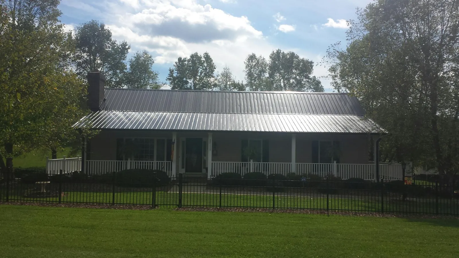 Gray metal roof on a brick ranch with a full width front porch in Princeton