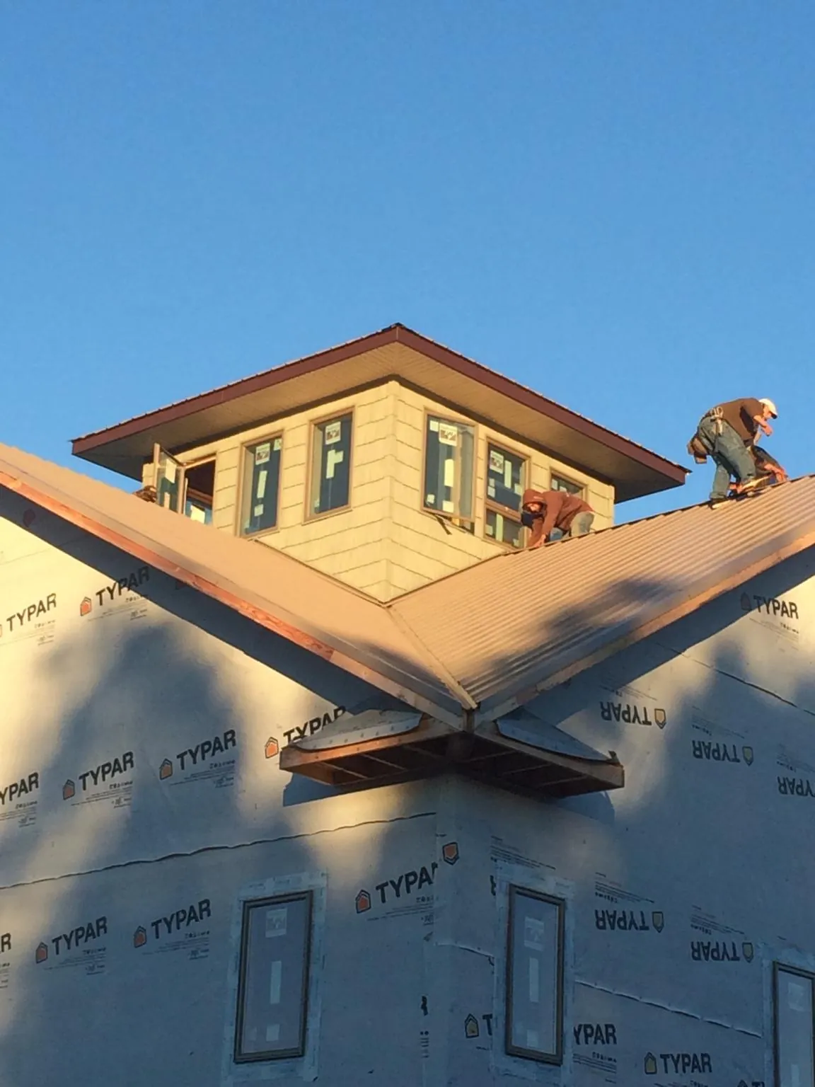Roofers working around a rooftop cupola on a new metal roof at sunset — Roof Waterproofing in Princeton by Roofing Brothers